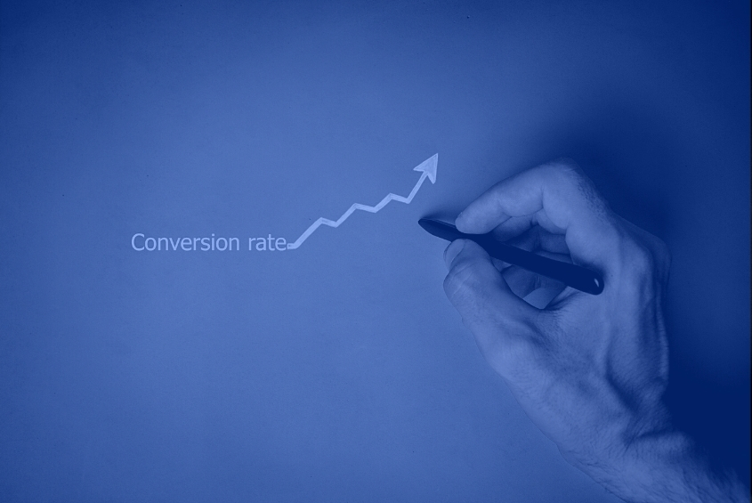 Close-up of hand holding a pen with a conversion rate arrow that’s increasing