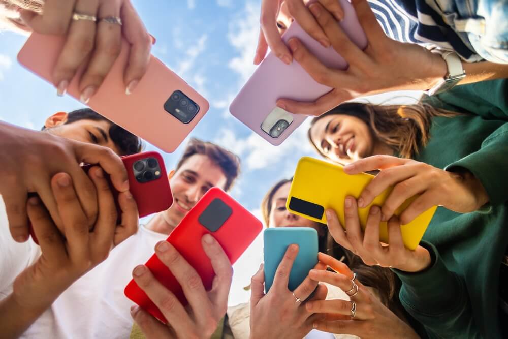A diverse team circles outdoors with phones, symbolizing SEO and digital marketing.
