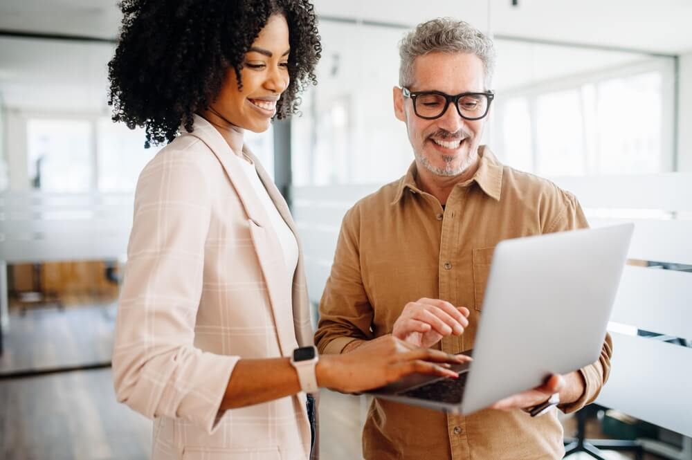 Two marketers at a digital marketing agency review SEO and content strategy on a laptop.