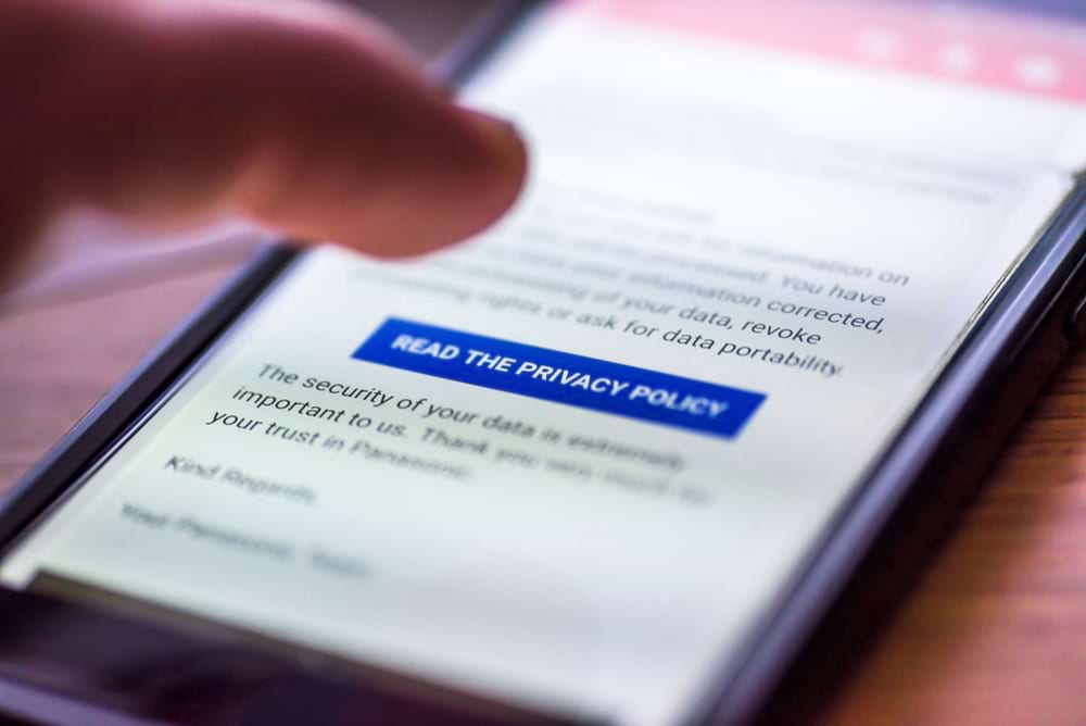 A finger taps a smartphone screen showing digital marketing and privacy policy info.