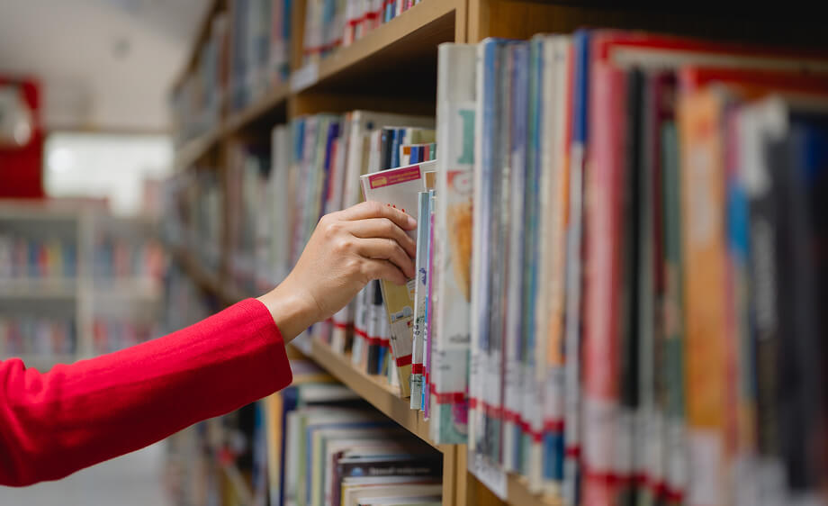 A person in red reaches for a book on digital marketing, SEO, and web development.