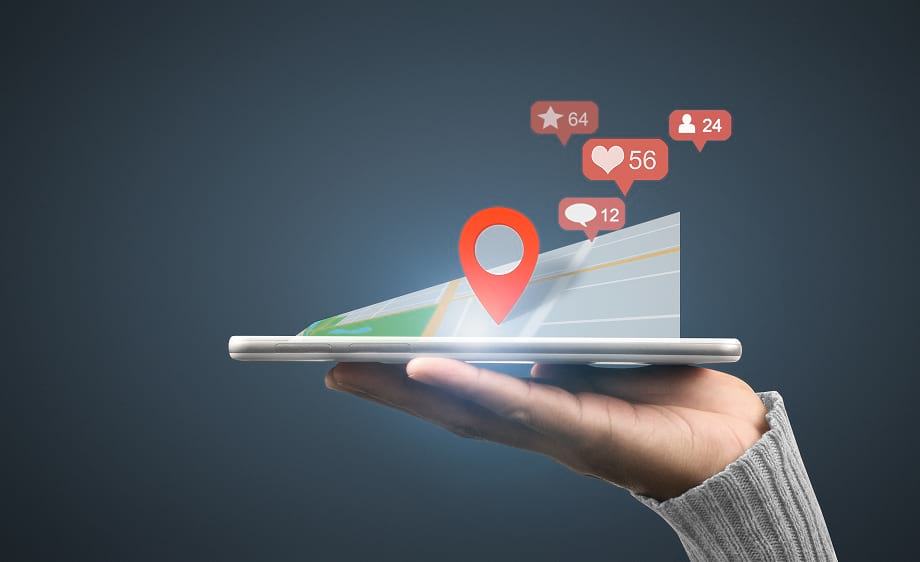 A hand holds a smartphone showing a map with social media marketing notifications.