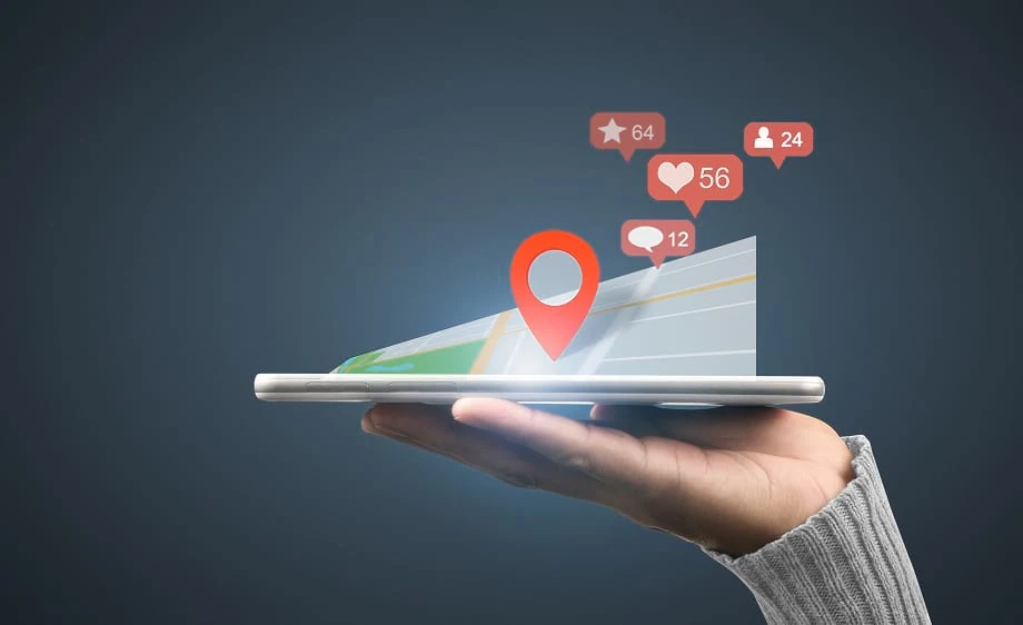 A hand holds a smartphone showing a map with social media marketing notifications.