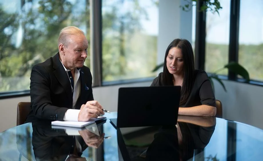 Two colleagues at a digital marketing agency discuss SEO and content strategy at a laptop.