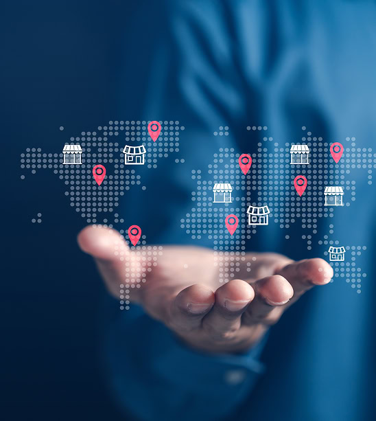 A hand displays a digital world map with store icons and pins, symbolizing global reach through SEO, content marketing, and web development.
