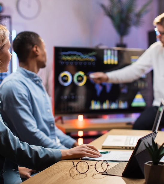 Digital marketing agency team analyzes SEO and paid media data on screen in office.