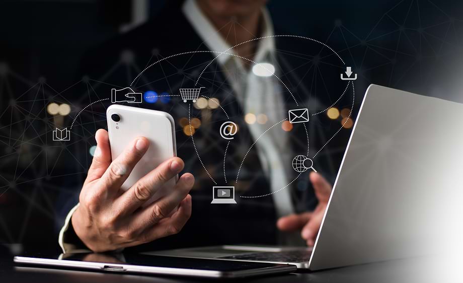 A person uses a smartphone and laptop with icons for social media marketing, SEO, and paid media agency services.