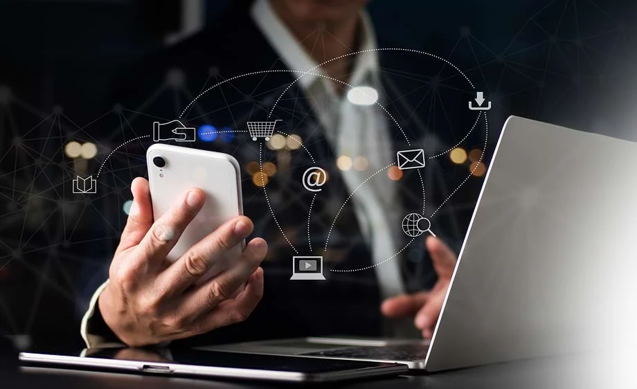 A person uses a smartphone and laptop with icons for social media marketing, SEO, and paid media agency services.