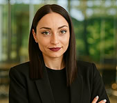 A woman in a black blazer stands in an office, representing a digital marketing agency.