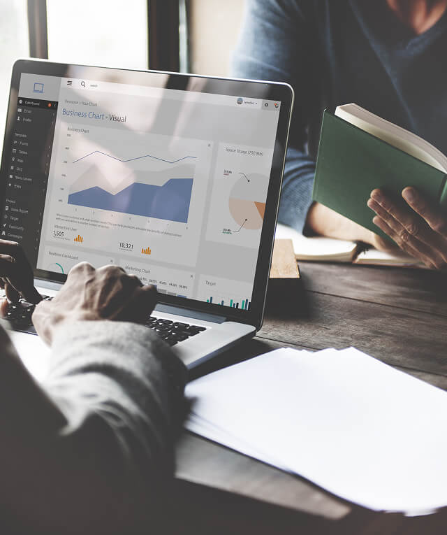 Two people at a desk review ecommerce marketing charts on a laptop for a digital marketing agency.