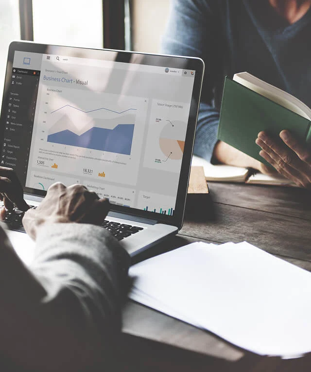 Two people at a desk review ecommerce marketing charts on a laptop for a digital marketing agency.