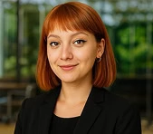 Woman digital marketing agency expert with red hair in black blazer indoors.
