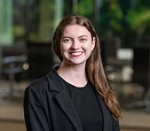 A woman in business attire smiles at a digital marketing agency office workspace.