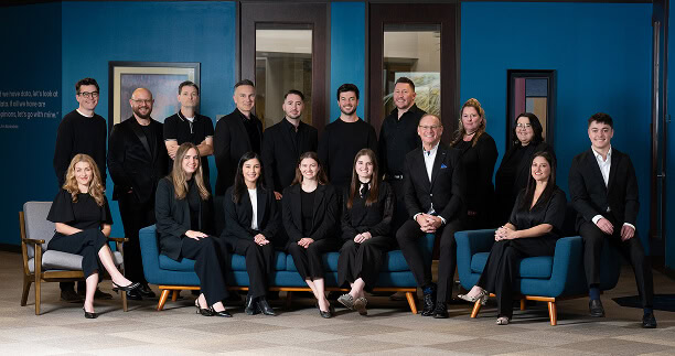 Team of digital marketing professionals posing in office with a blue wall background.