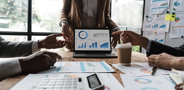 Three people analyze SEO, content marketing, and paid media charts in a digital marketing agency meeting.
