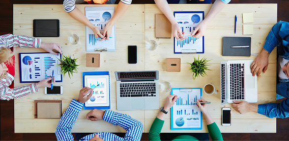 Digital marketing agency team discusses SEO, content marketing, and paid media strategies around a table.