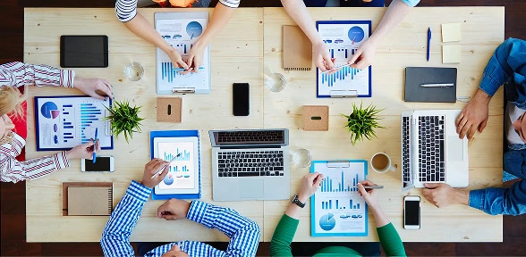 Digital marketing agency team discusses SEO, content marketing, and paid media strategies around a table.