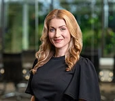 A woman at a digital marketing agency stands indoors with office windows behind her.