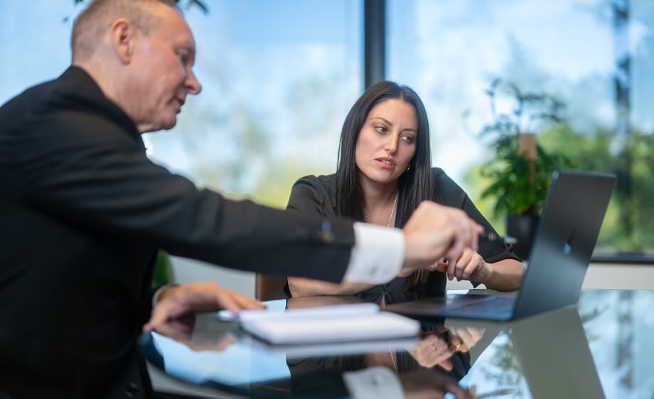 Two colleagues at a digital marketing agency discuss SEO services over a laptop.