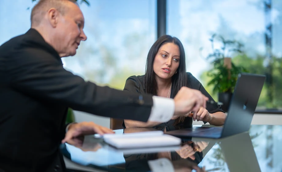 Two colleagues at a digital marketing agency discuss SEO services over a laptop.