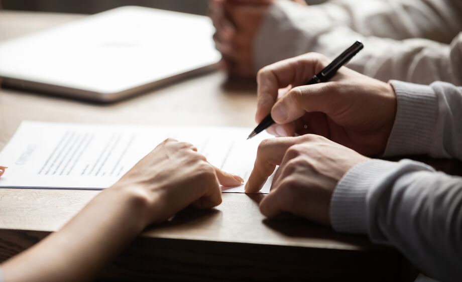 Two people at a table review SEO services contract at a digital marketing agency.