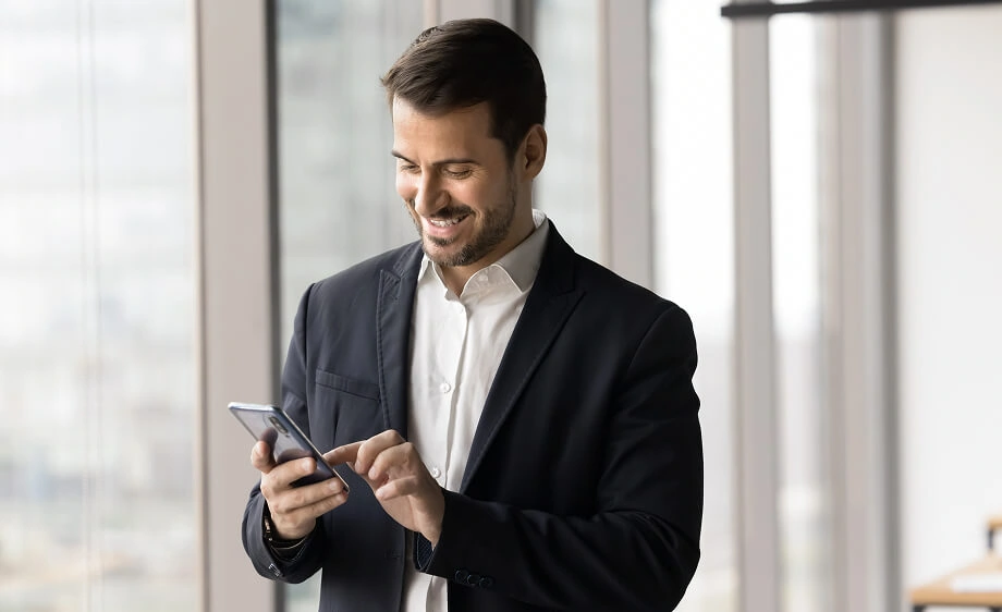 A man in a suit uses his smartphone for SEO and call tracking at a digital marketing agency.