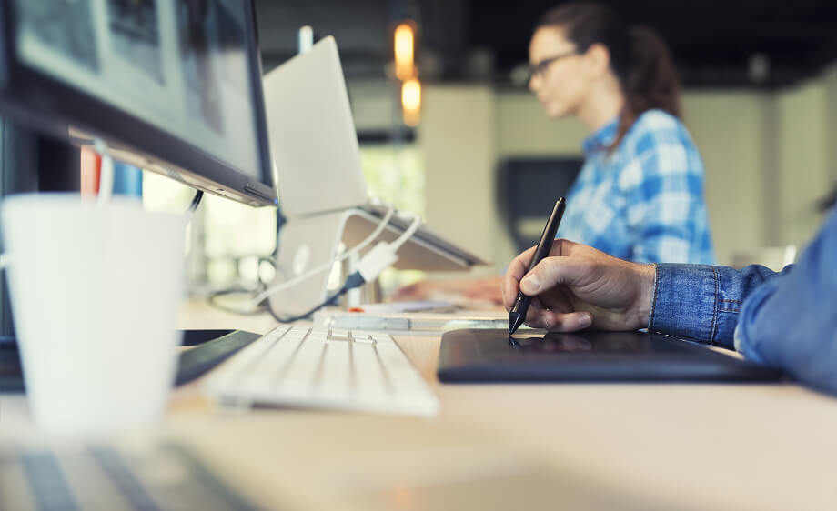 A marketer uses a pen tablet at a digital marketing agency office workspace.