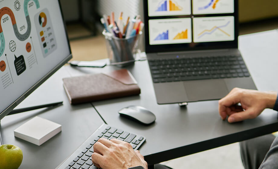 Two marketers at a desk analyze SEO, content marketing, and web development data.
