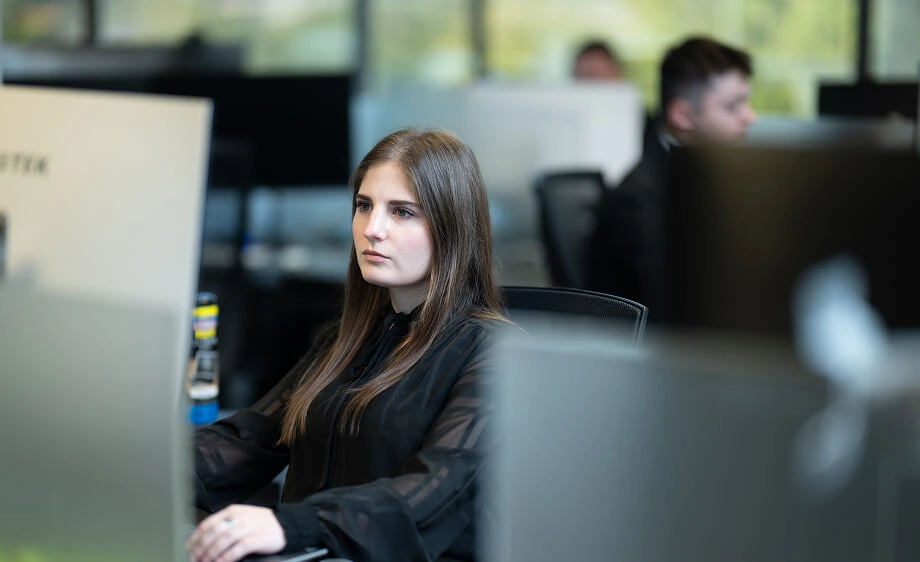 A woman at a digital marketing agency designs a landing page as her team discusses SEO.