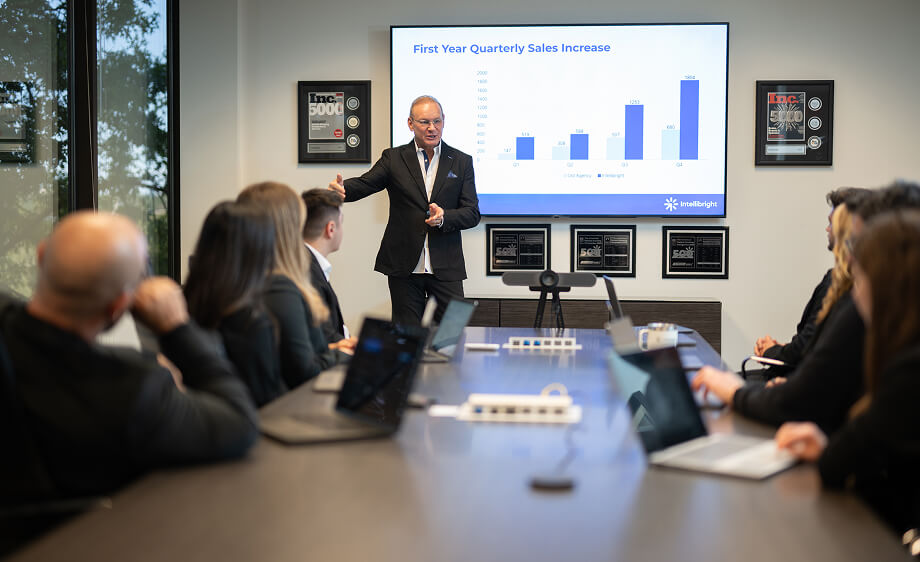 A digital marketing agency expert shows Google Ads growth to colleagues in a meeting.