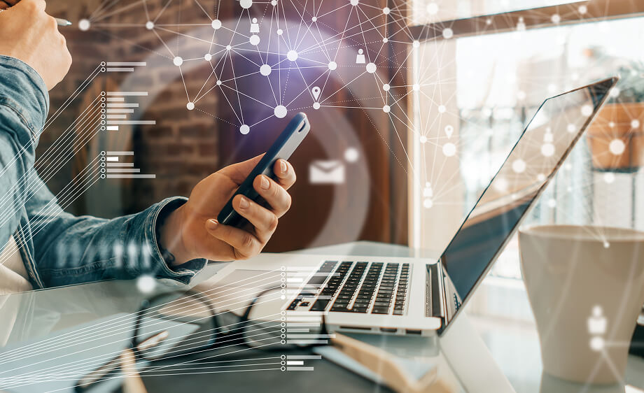 A person using a smartphone and laptop with network graphics represents a digital marketing agency, SEO services, content marketing, and social media marketing.