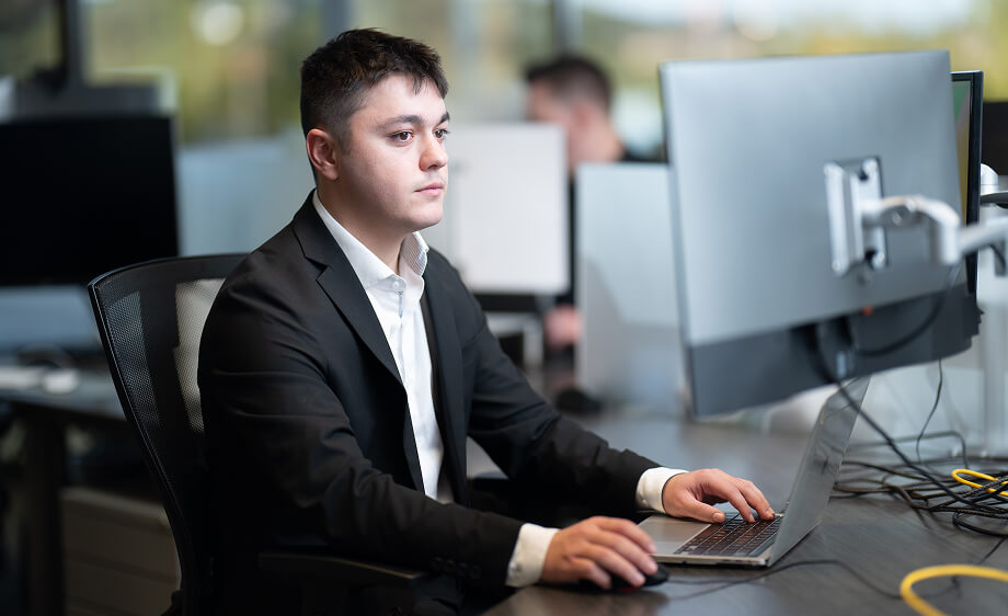 A man in a suit works at a computer in a digital marketing agency office.
