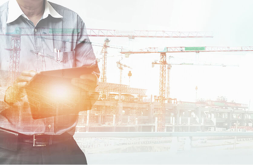 A professional uses a tablet at a construction site for digital marketing services.
