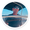 John Geary, a digital marketing agency expert, steers a boat under blue skies.