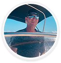 John Geary, a digital marketing agency expert, steers a boat under blue skies.