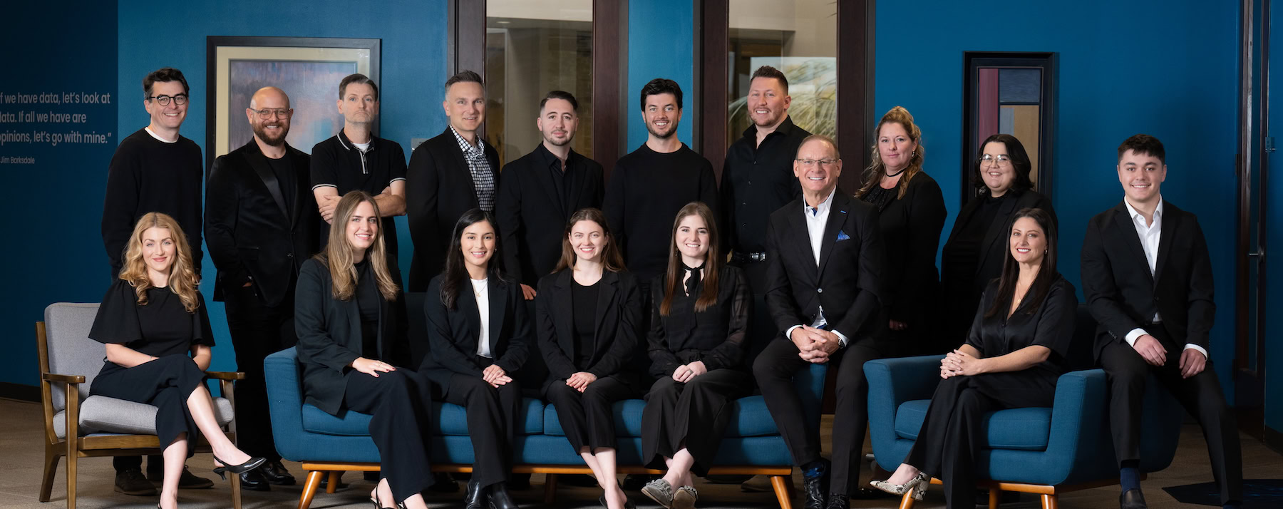 Sixteen digital marketing agency team members pose in a modern office setting.