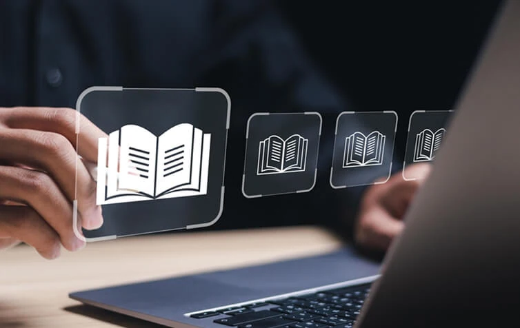 A person using a laptop taps a virtual screen with book icons, symbolizing SEO and digital marketing strategies.