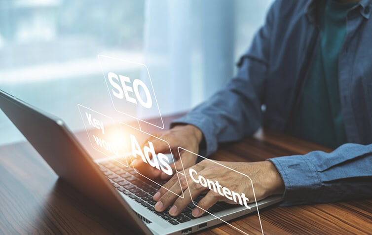 Marketer at laptop with virtual SEO, content marketing, and paid media agency terms.