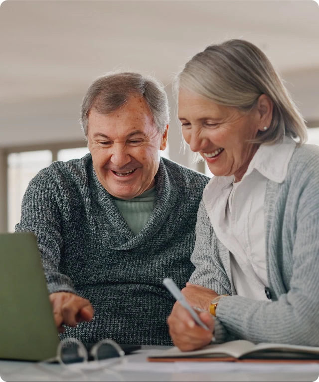 Smiling seniors research digital marketing agency seo services and content marketing on a laptop.