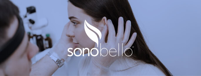 A healthcare provider examines a woman's face, Sono Bello logo, for digital marketing agency use.