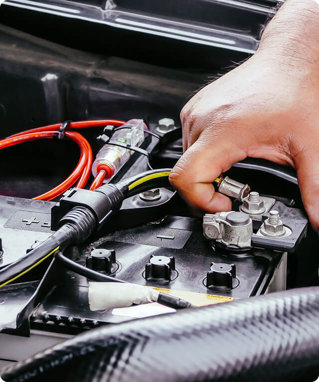 A hand connects a cable to a car battery, symbolizing digital marketing agency solutions.