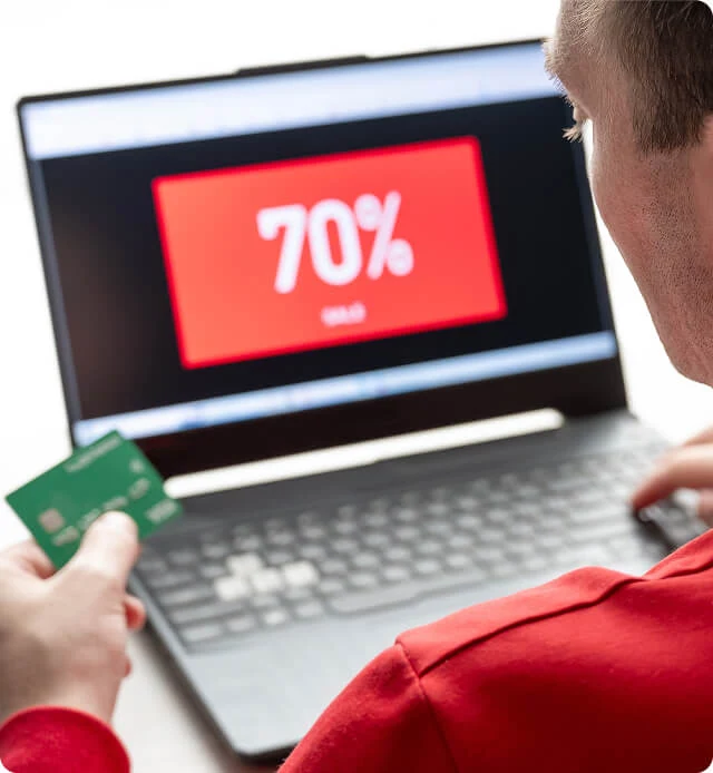 A person uses a credit card for online Black Friday shopping on a laptop, showing digital marketing and paid media agency success.