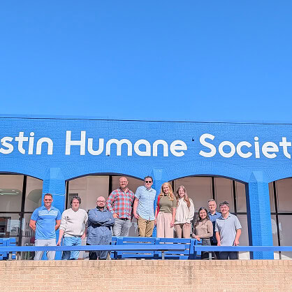 Nine digital marketing agency team members stand before the Austin Humane Society sign.