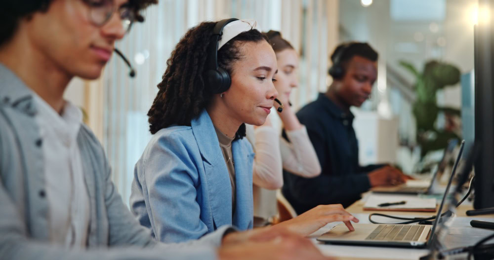 Four digital marketing agency team members with headsets work on SEO and social media at computers.