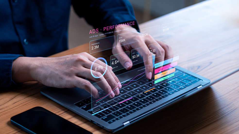 Hands typing on a laptop with holographic digital marketing agency metrics.